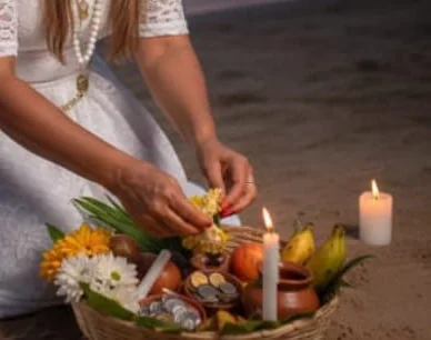 Detalhe de velas acesas ao lado de uma oferenda com flores e frutas